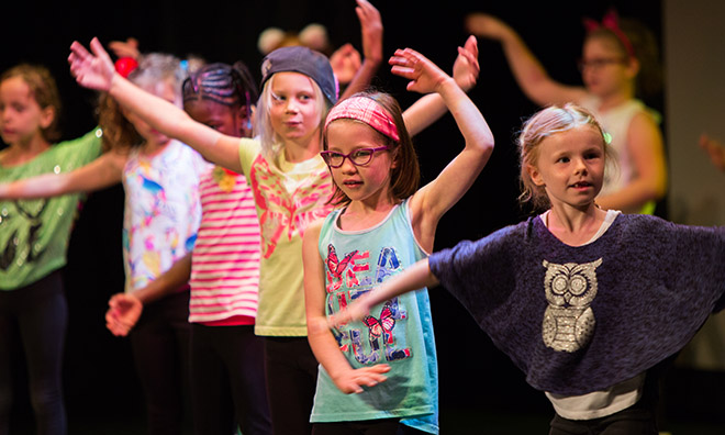  Many young girls on stage performing and posing. 