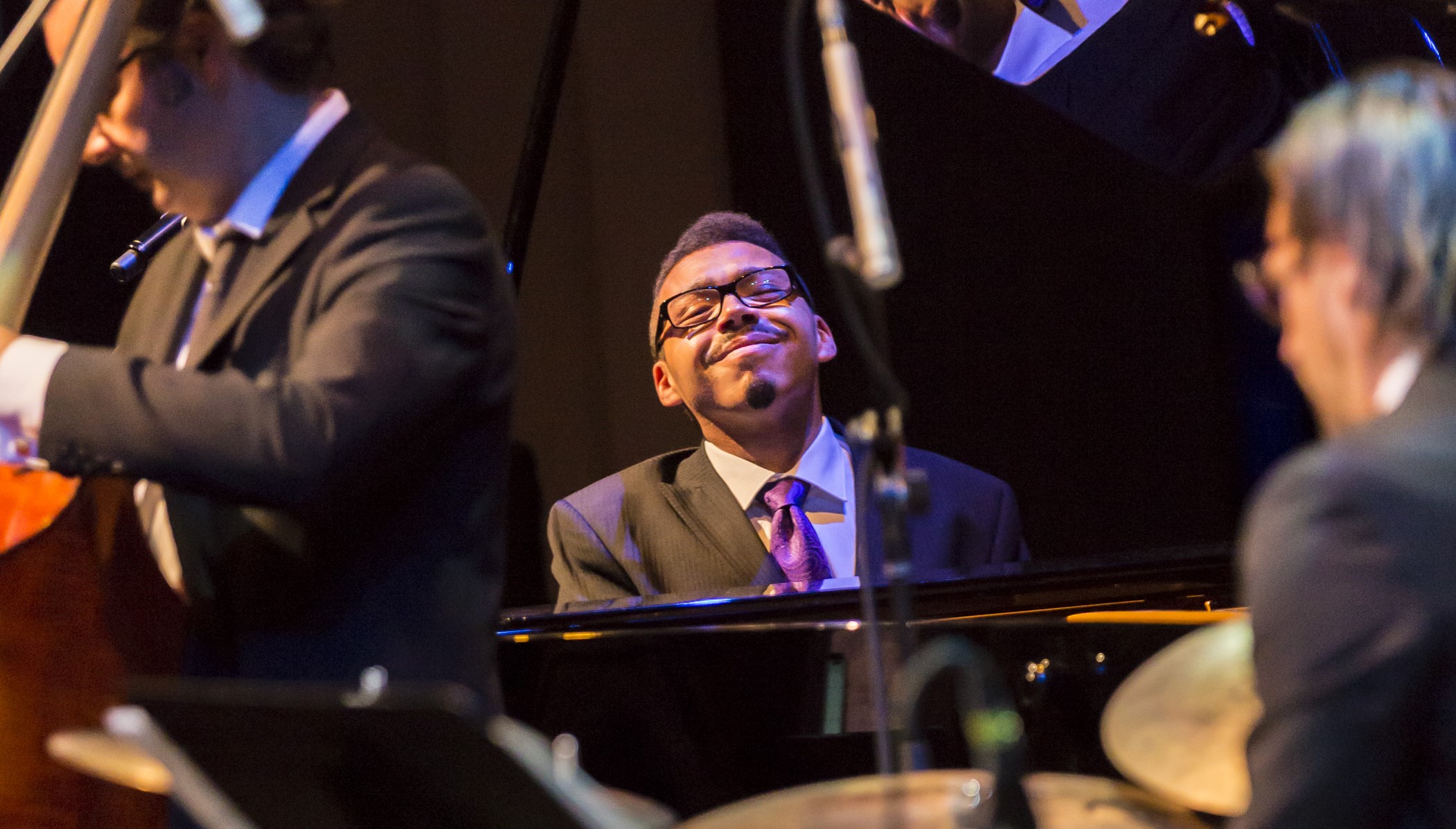  James Clarke on piano surrounded by a percussionist and stand up bass player. 